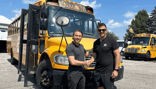 Men posing in front of school bus from Buses for Sale