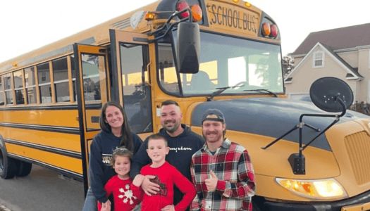 Family posing in front of school bus from Buses for Sale